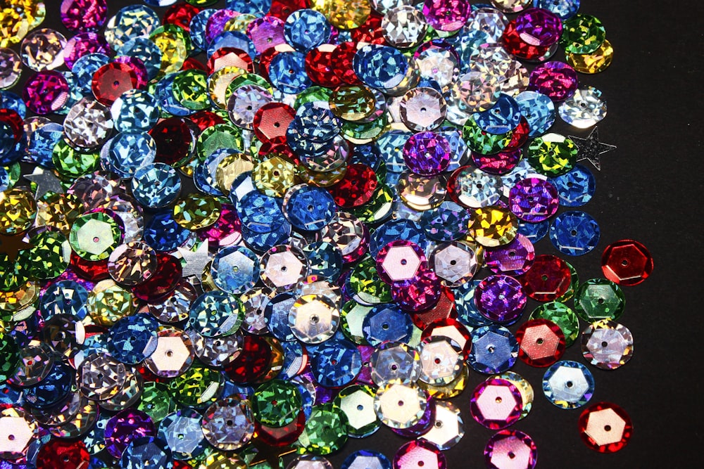 a pile of different colored jewel stones on a black surface