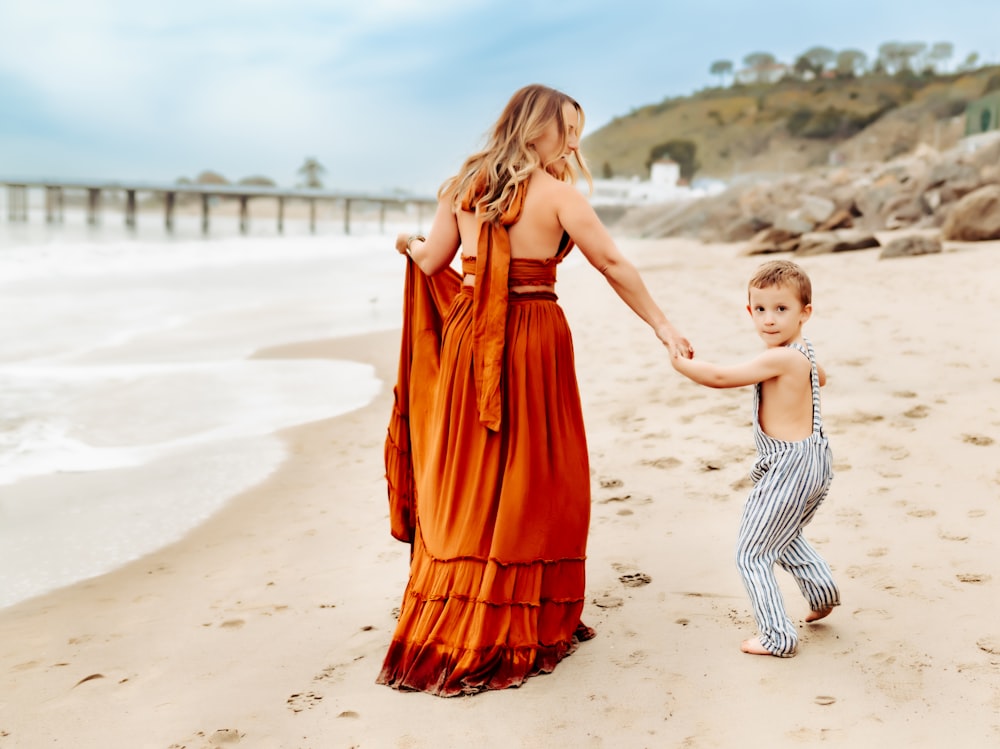 a woman and a child holding hands on a beach