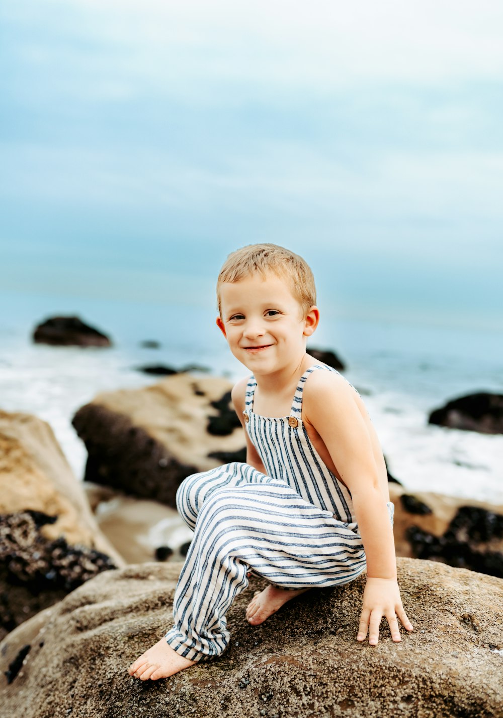 a little boy that is sitting on a rock