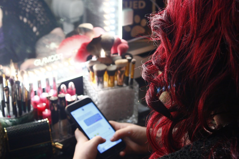 Une femme aux cheveux roux regarde son téléphone portable