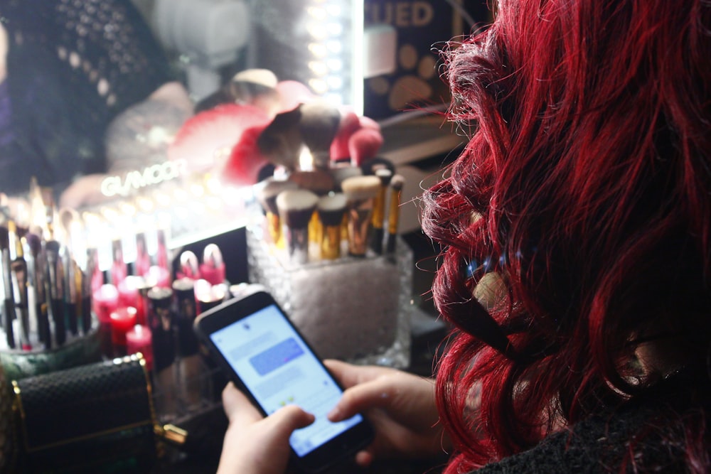 a woman with red hair is looking at her cell phone