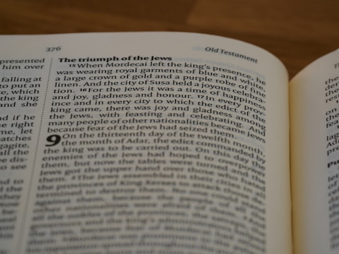 A close-up of an open book focusing on a page with a passage titled 'The triumph of the Jews.' The text discusses Mordecai and a celebration of happiness and joy in a biblical context. The page number 376 is visible, and the header indicates it's from the Old Testament.