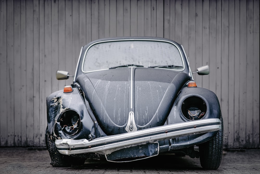 an old vw bug is parked in front of a building