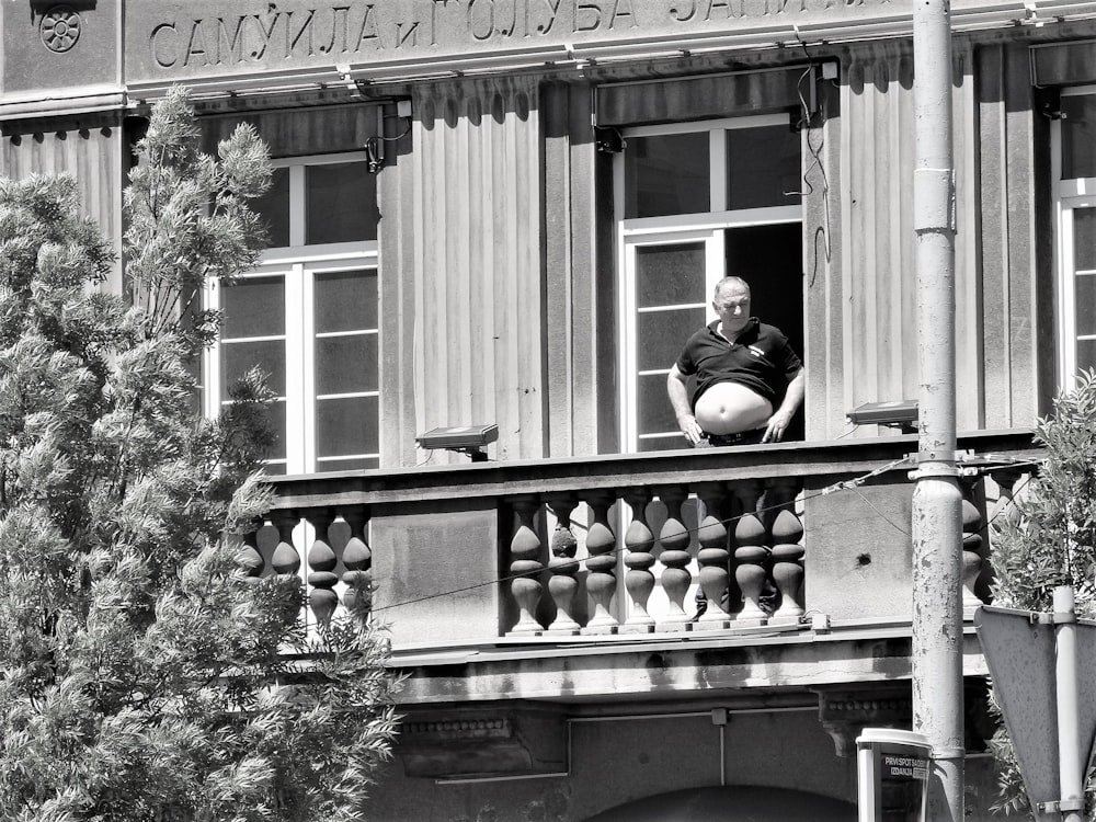 a black and white photo of a man sitting on a balcony