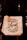 A canvas tote bag hangs against a dark background. The bag features bold, black text that reads 'Support Local Farmers,' accompanied by minimalist decorative elements like wheat stalks. There's a small tag attached to the bag's handle.