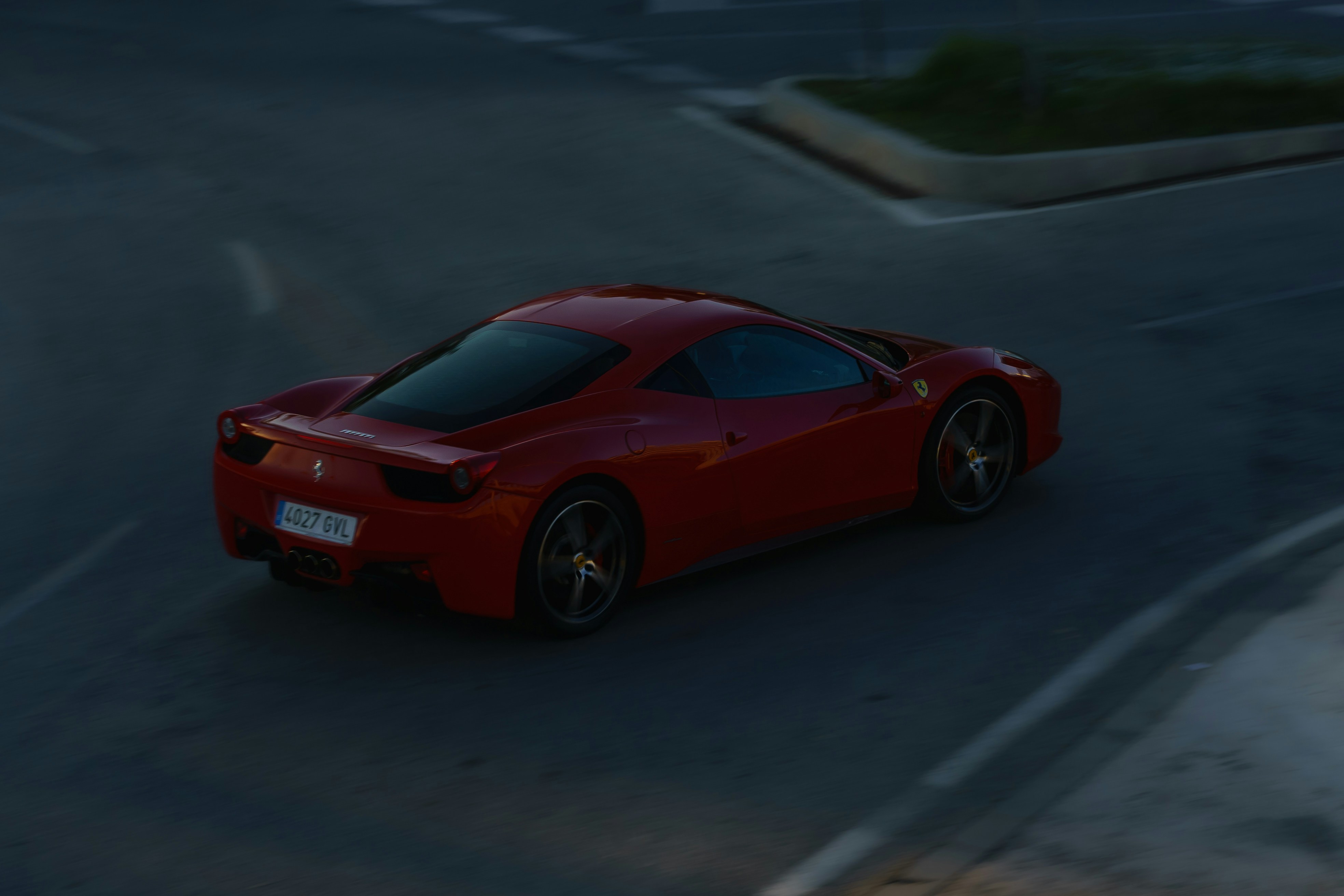 Red Ferrari 458 Italia sports car on empty road, dramatic low-key lighting, dark moody sky