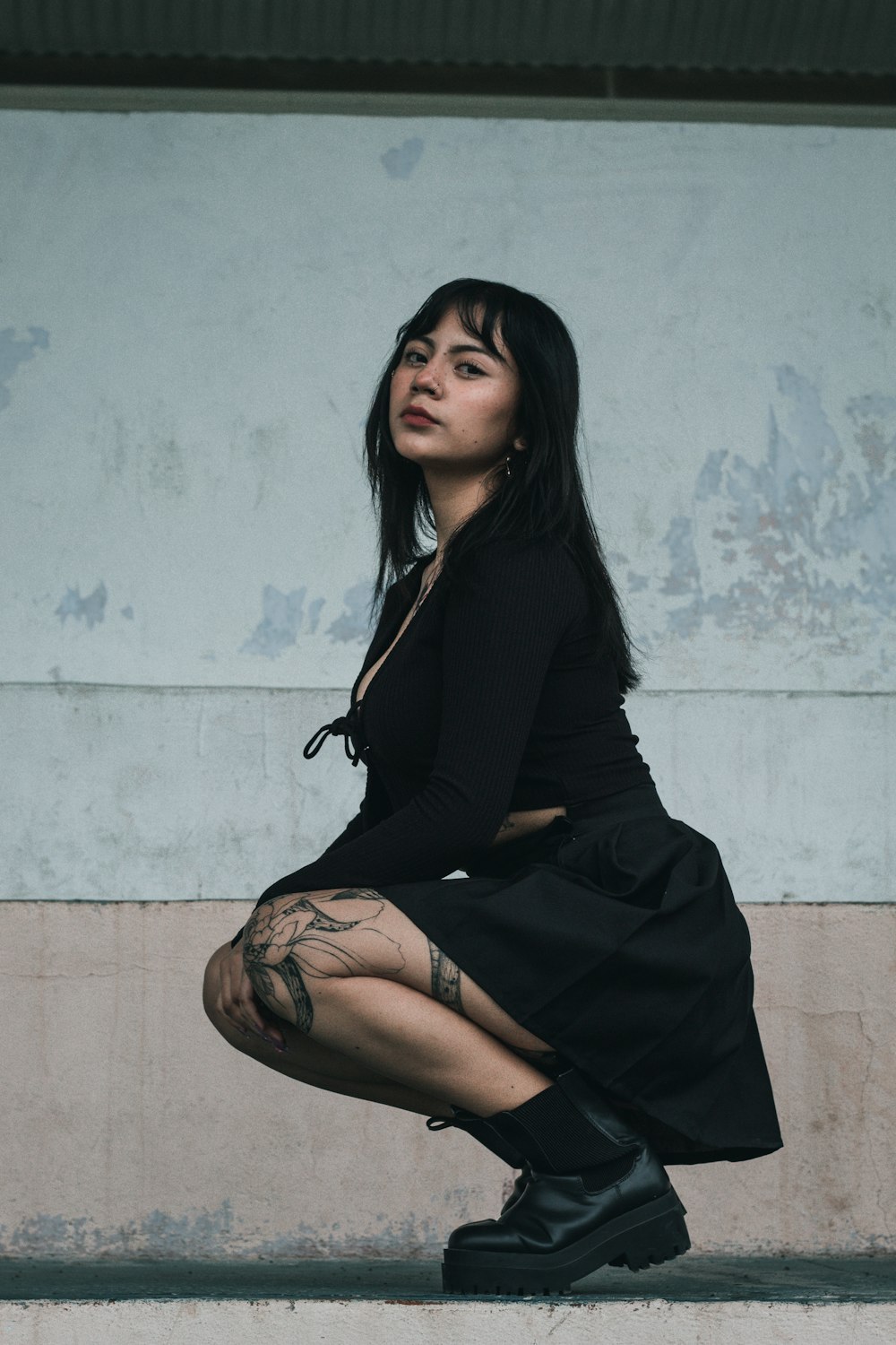 a woman sitting on a ledge with her legs crossed