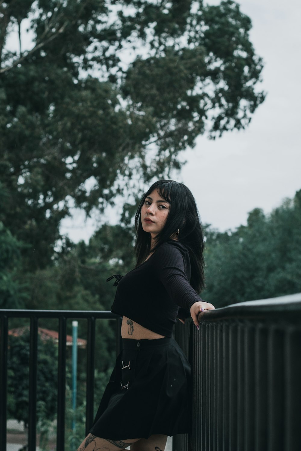 a woman leaning on a fence with her hands on her hips