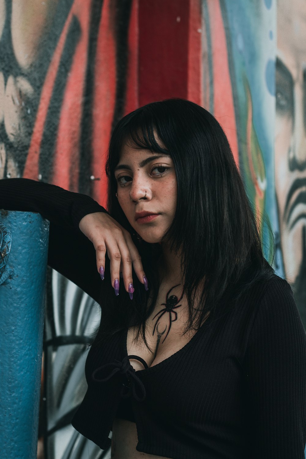 a woman standing in front of a graffiti covered wall