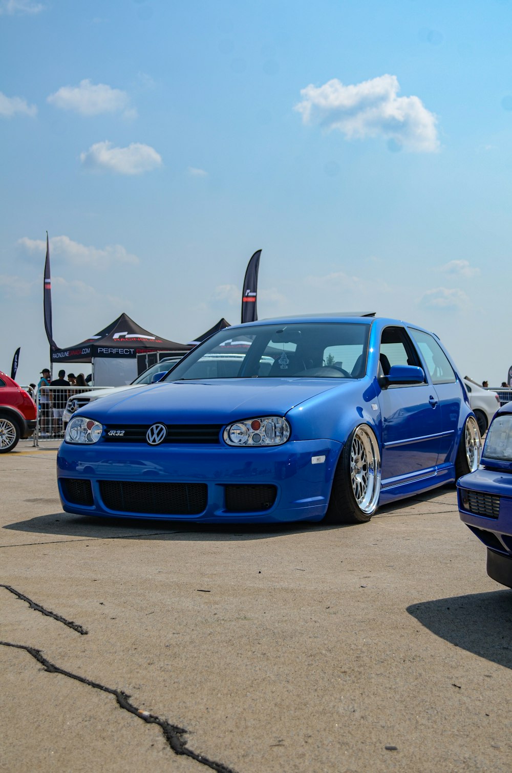 a blue car parked in a parking lot next to other cars