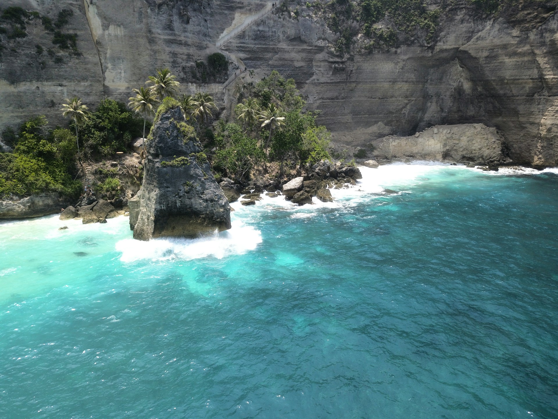 The turquoise waters and sandy shores of Antalya's beach, framed by lush greenery and sunlit cliffs.