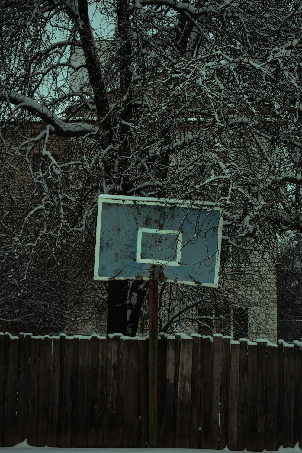 a basketball hoop in the snow near a fence