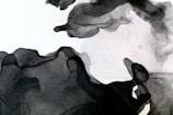 Abstract black and white ink wash art with flowing, organic shapes. The gradients and textures create a sense of movement and depth.