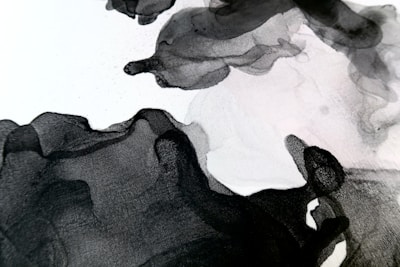 Abstract black and white ink wash art with flowing, organic shapes. The gradients and textures create a sense of movement and depth.