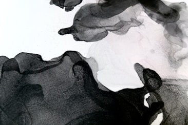 Abstract black and white ink wash art with flowing, organic shapes. The gradients and textures create a sense of movement and depth.