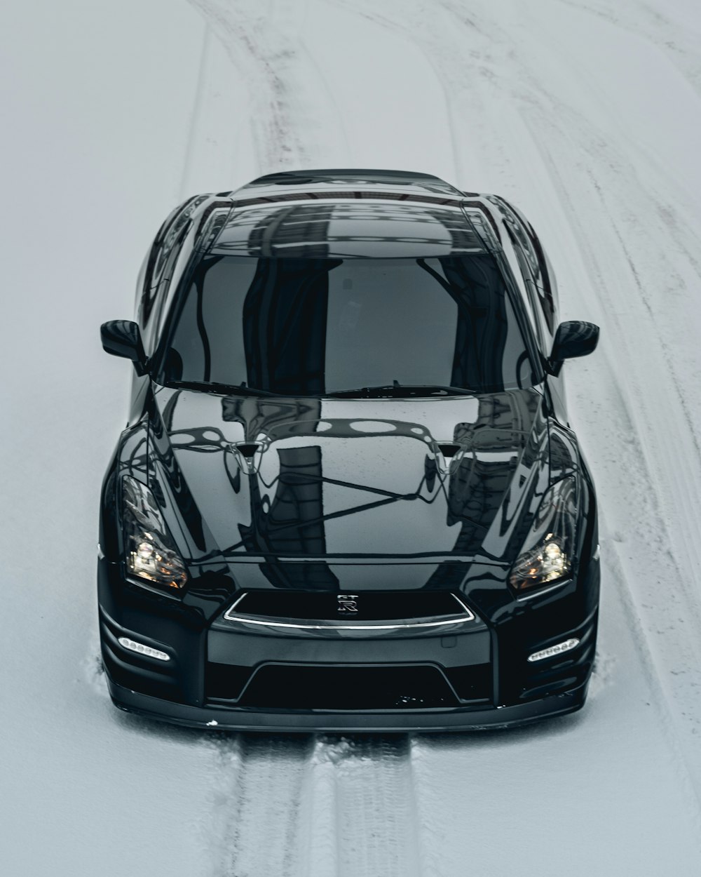 a black car driving down a snow covered road