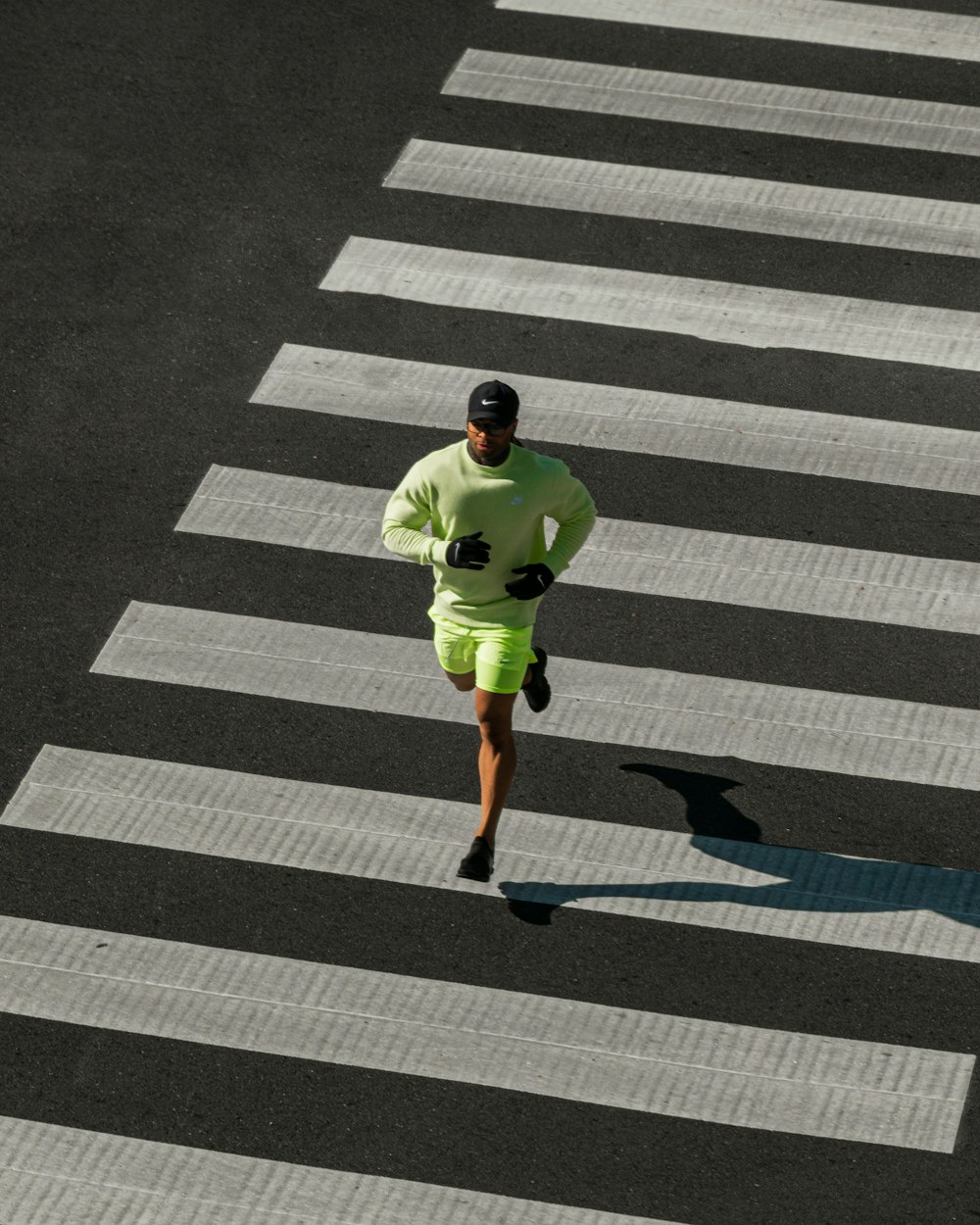 녹색 옷을 입은 남자가 거리를 가로질러 달리고 있다