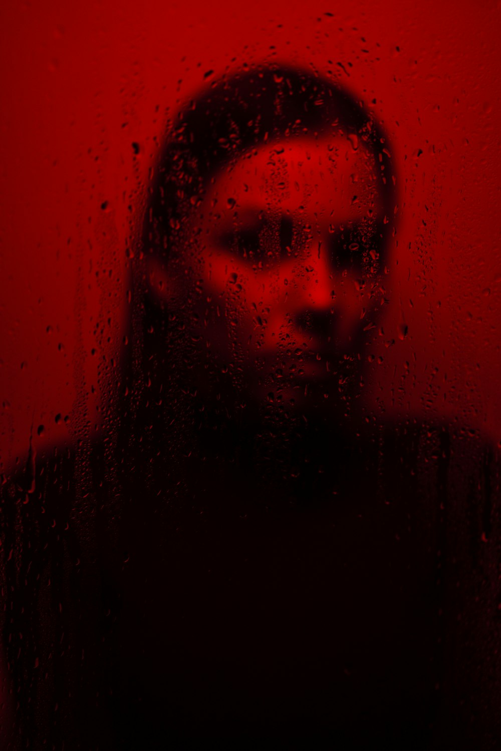 a woman standing in front of a window covered in rain