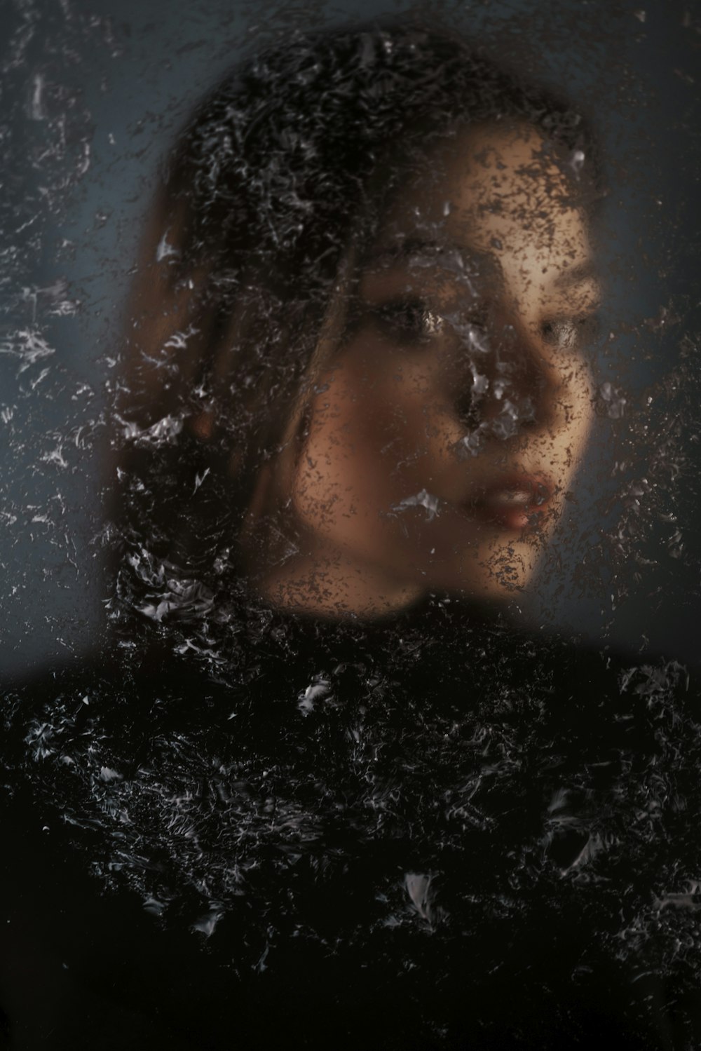 a woman looking out of a window covered in snow