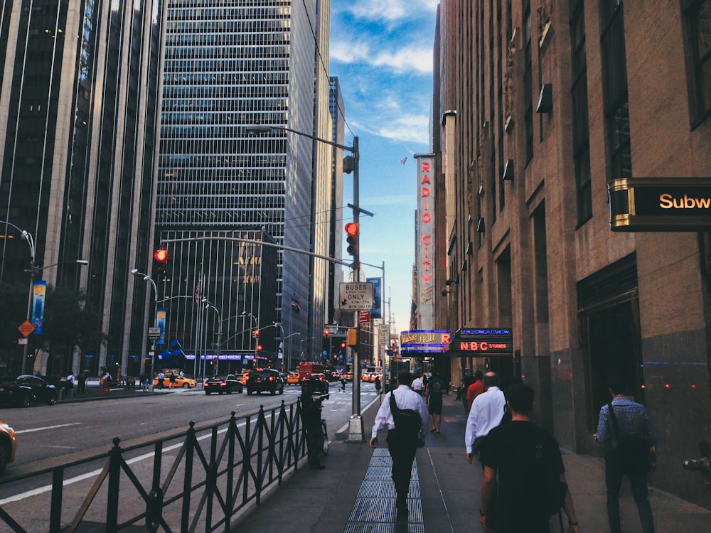 a group of people walking down a street next to tall buildings