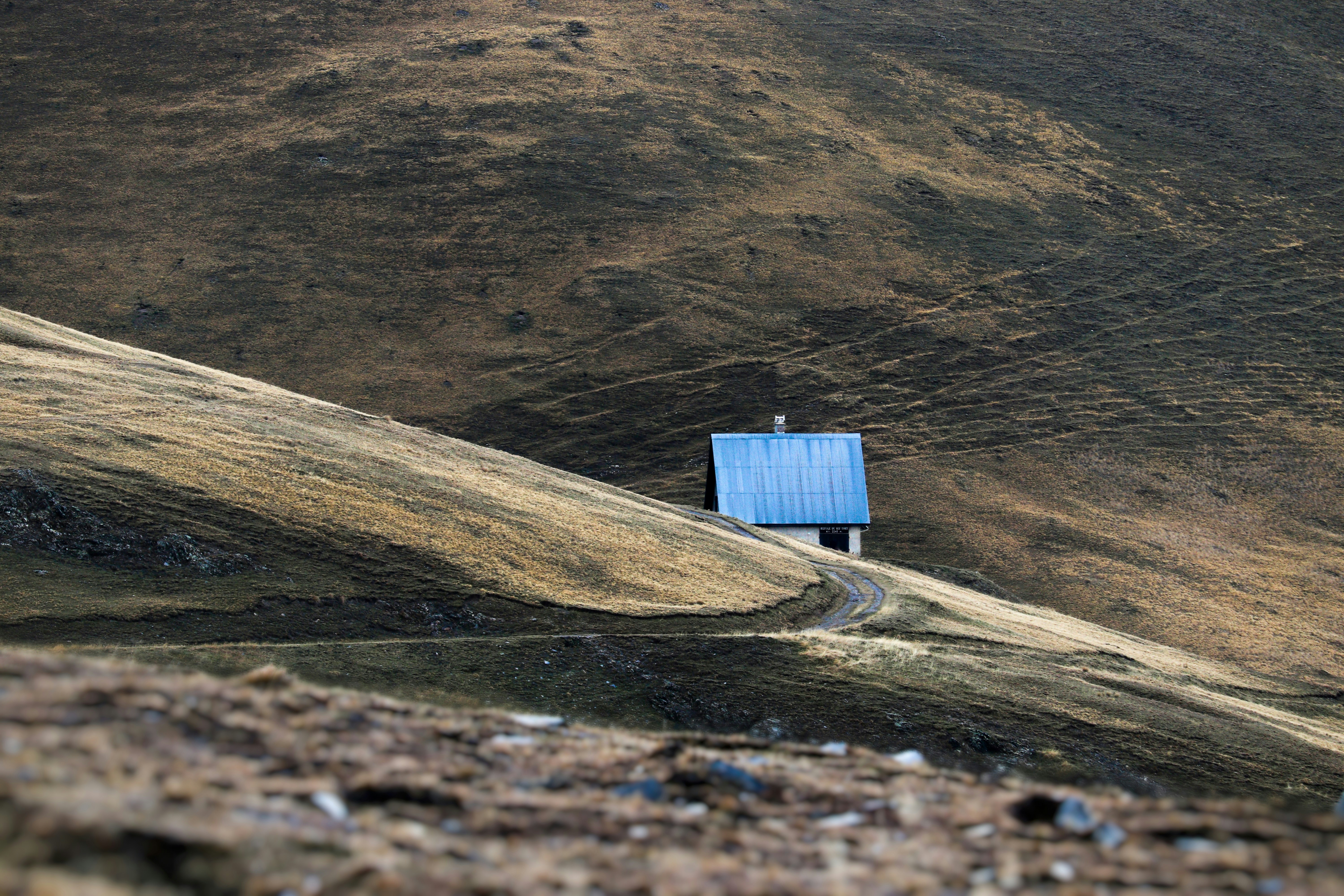 a small blue house on a hill with mountains in the background