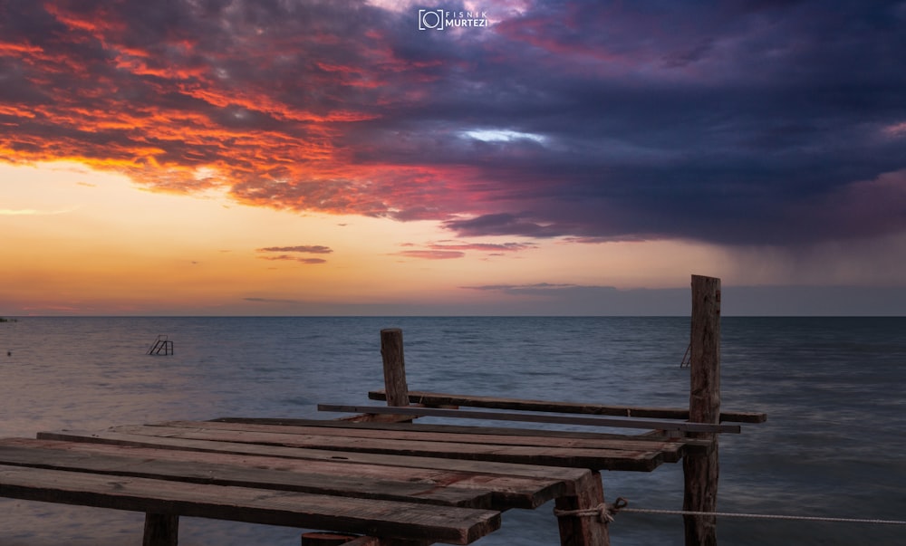 a wooden dock sitting on top of a body of water under a cloudy sky