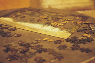 A cozy scene of hands assembling a colorful jigsaw puzzle on a wooden table with soft natural light.