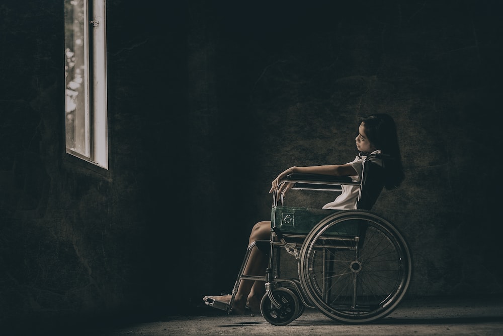 uma mulher em uma cadeira de rodas olhando para fora de uma janela