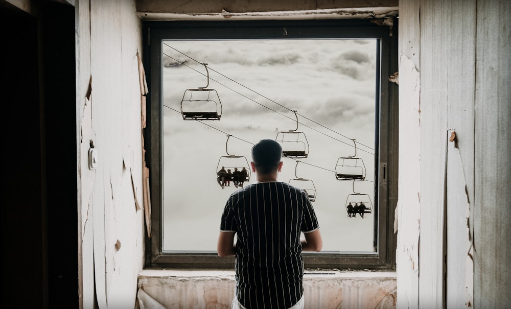 a man looking out a window at a ski lift