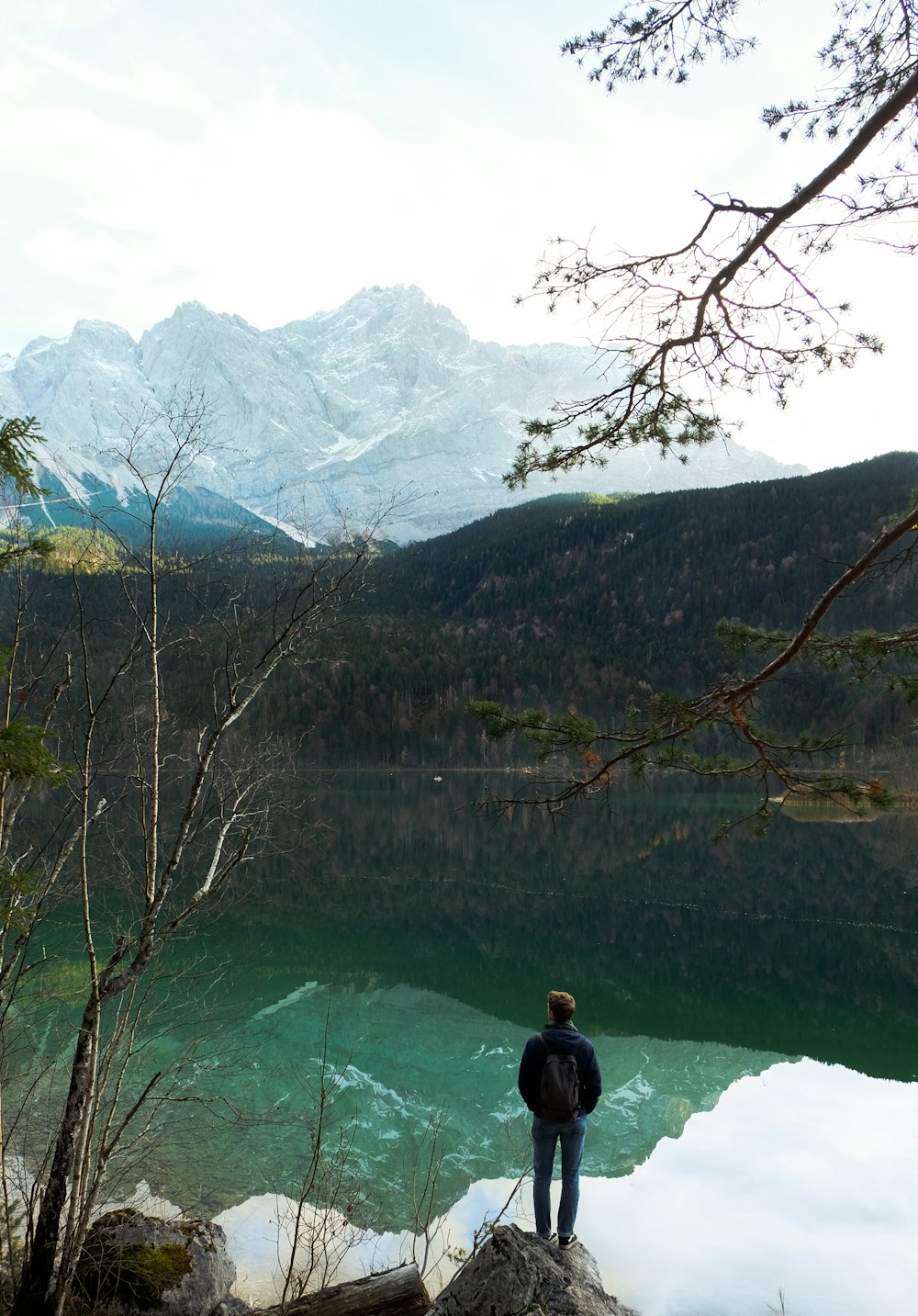 a person standing on a rock overlooking a lake