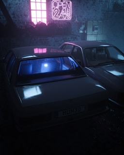 Two cars are parked in a dimly lit area with a neon sign that reads 'OPEN 24H' glowing in pink. The ambient light casts reflections on the cars, with a blue hue inside one car. There is a rustic, industrial backdrop featuring stone walls and electrical boxes.
