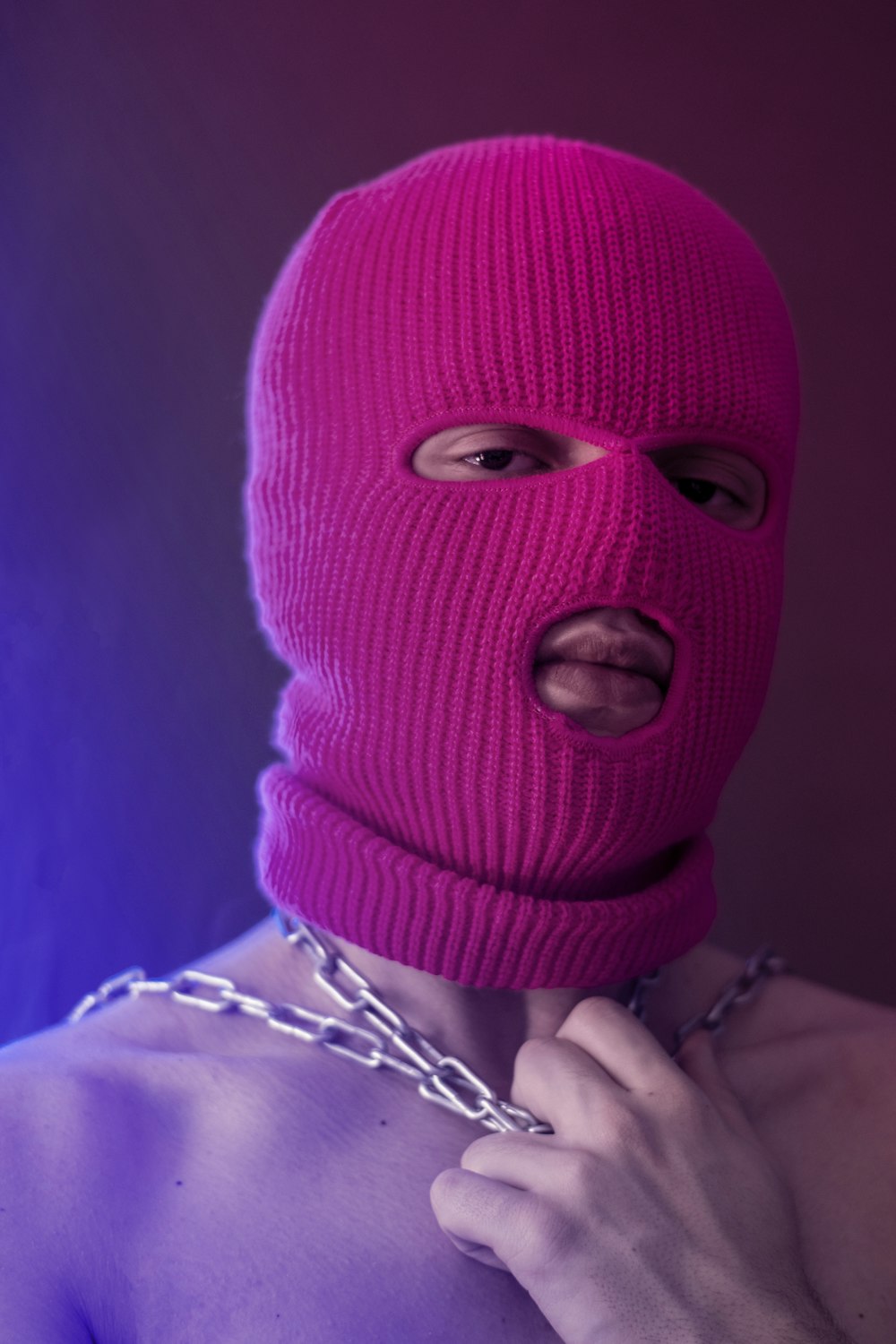 Un uomo che indossa una maschera rosa e una catena intorno al collo