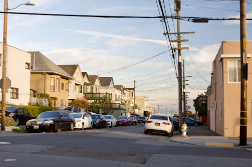 A calm residential street with various houses under a clear blue sky.