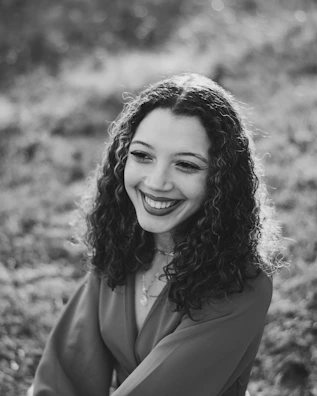 Portrait of a teacher with curly hair and a warm smile against a soft background.