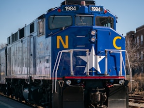 a blue train traveling down train tracks next to a building