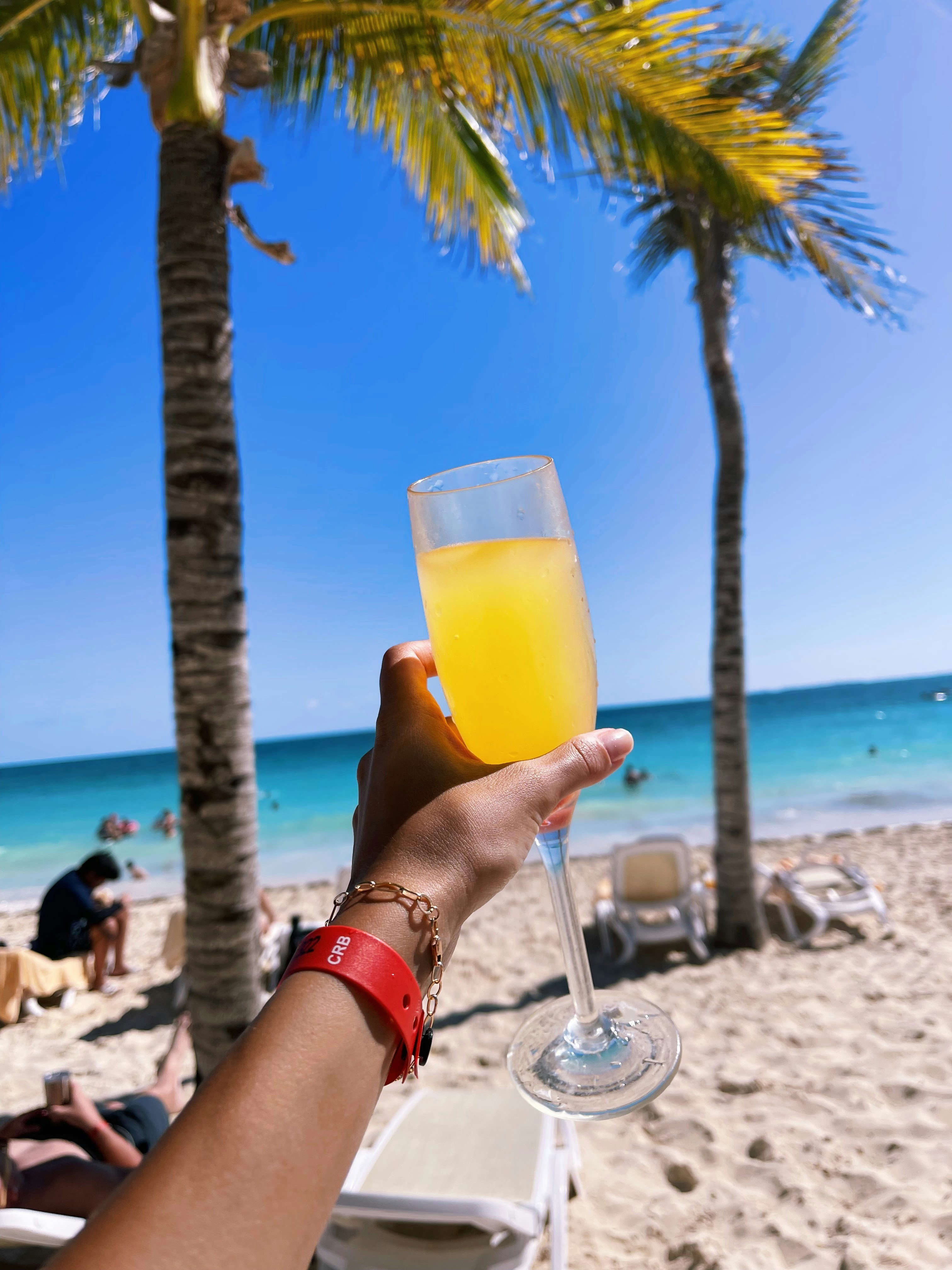 uma pessoa segurando um copo de suco de laranja em uma praia