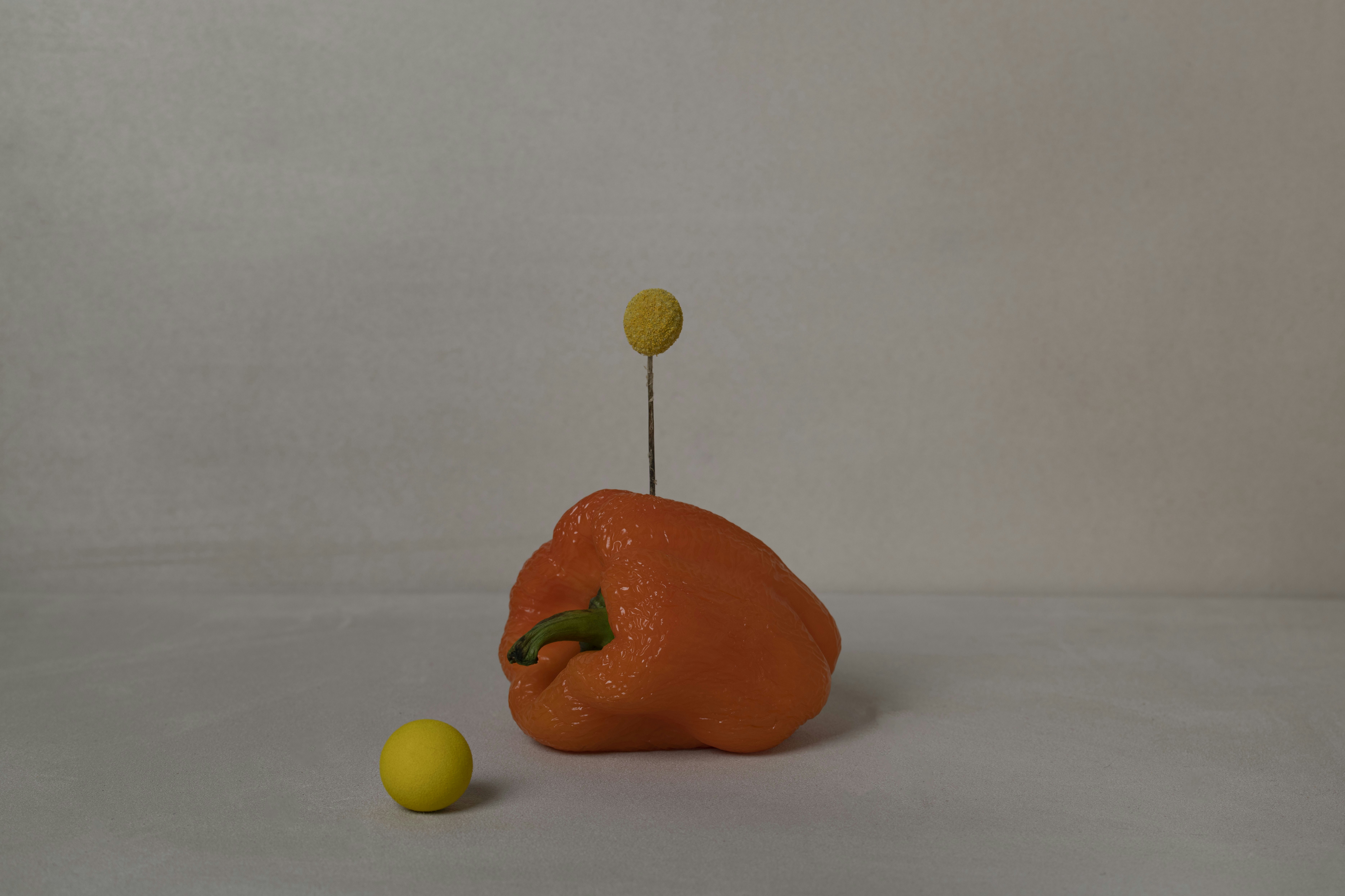 a small orange object sitting next to a yellow ball