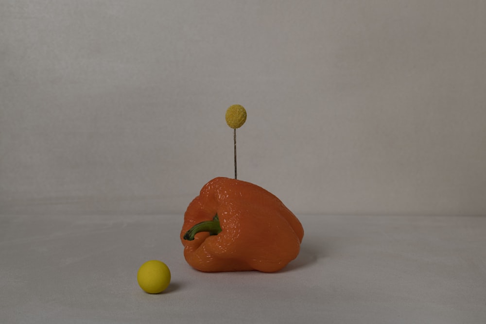 a small orange object sitting next to a yellow ball