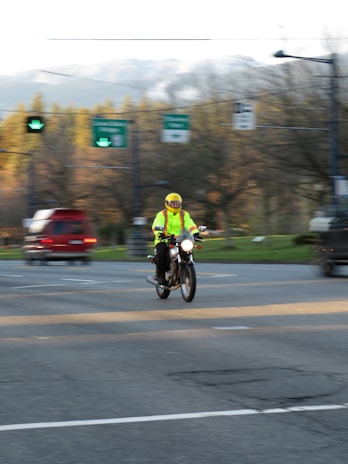 A group of riders wearing bright yellow jackets riding safely on a highway with clear road markings.