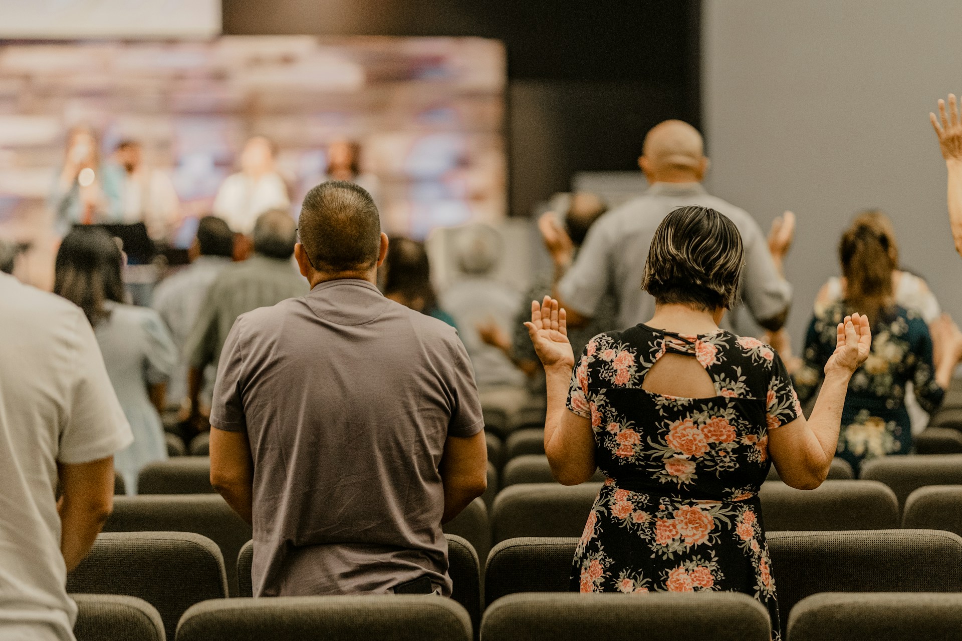 a group of people sitting in a room with their hands in the air