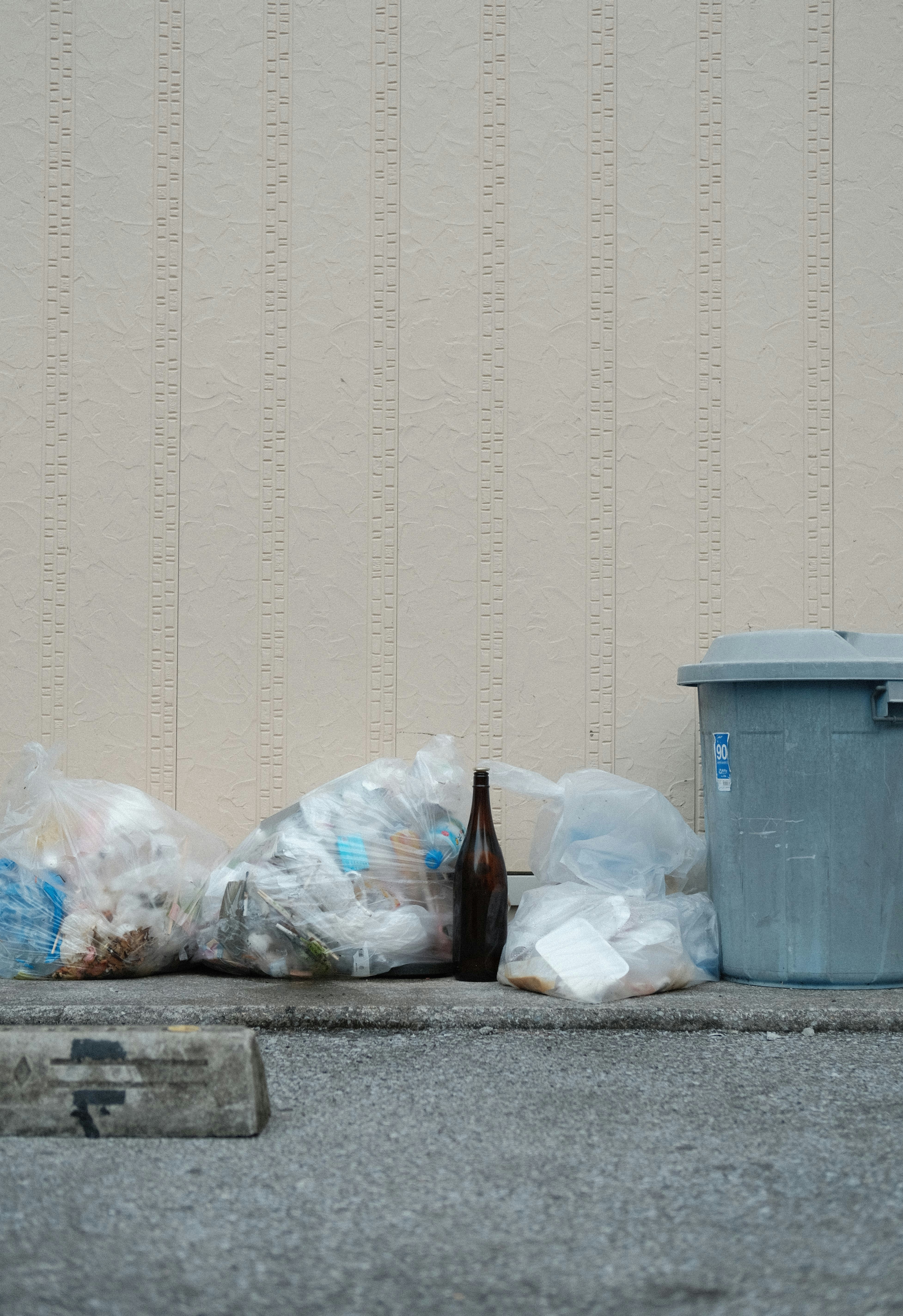 a blue trash can sitting on the side of a road