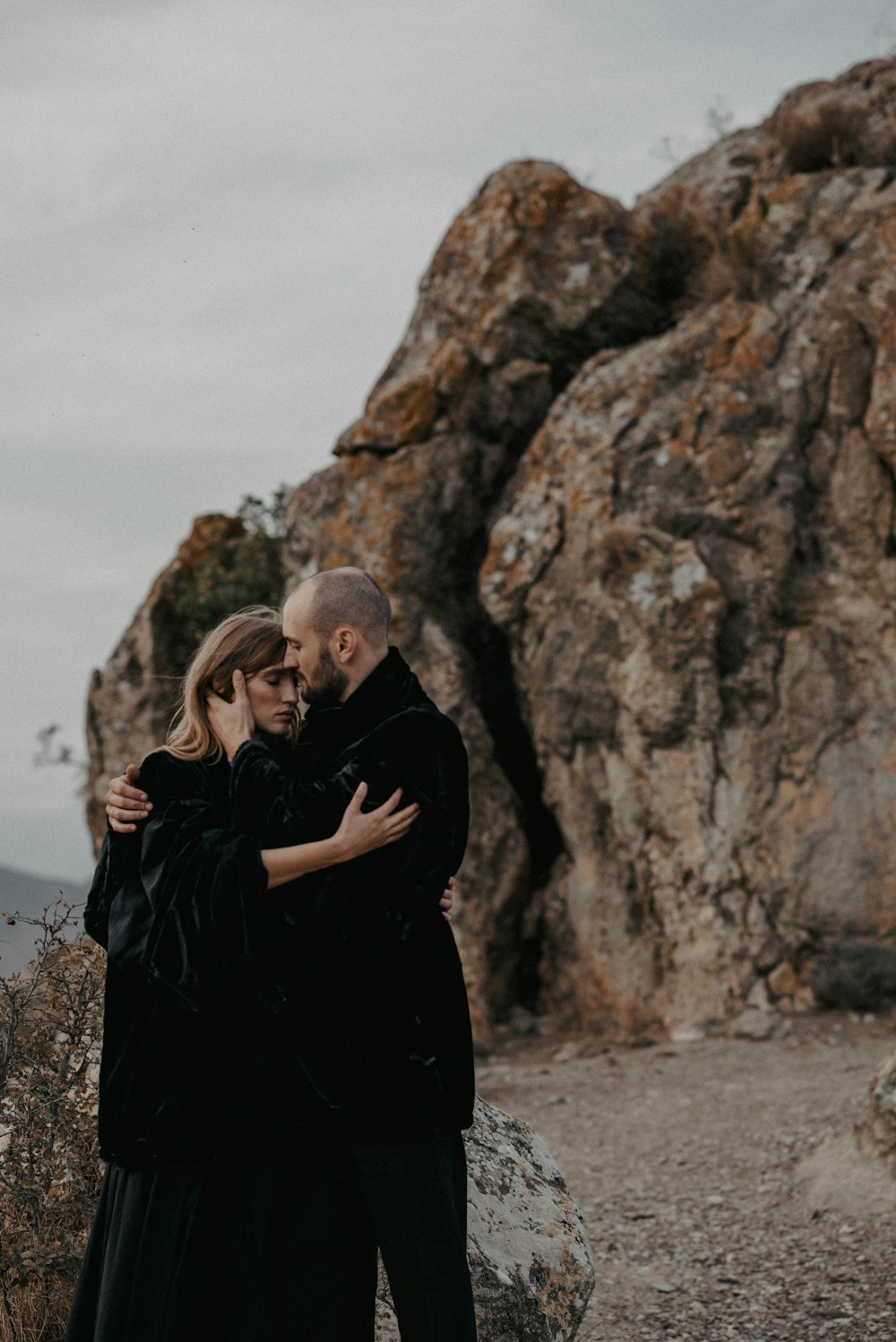 a man and a woman embracing in front of a mountain