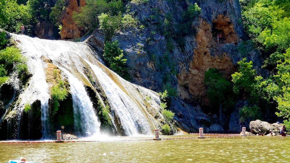 a group of people swimming in a body of water near a waterfall
