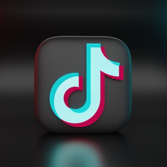 A 3D representation of a recognizable logo positioned at the center of the image. The logo is a stylized musical note with a combination of light blue and pink colors, set against a dark, glossy square background, creating a modern and sleek look.