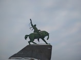 A proud horse with its rider holding a trophy in a sunny equestrian arena