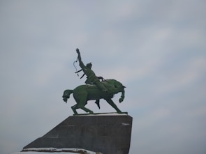 A proud horse with its rider holding a trophy in a sunny equestrian arena
