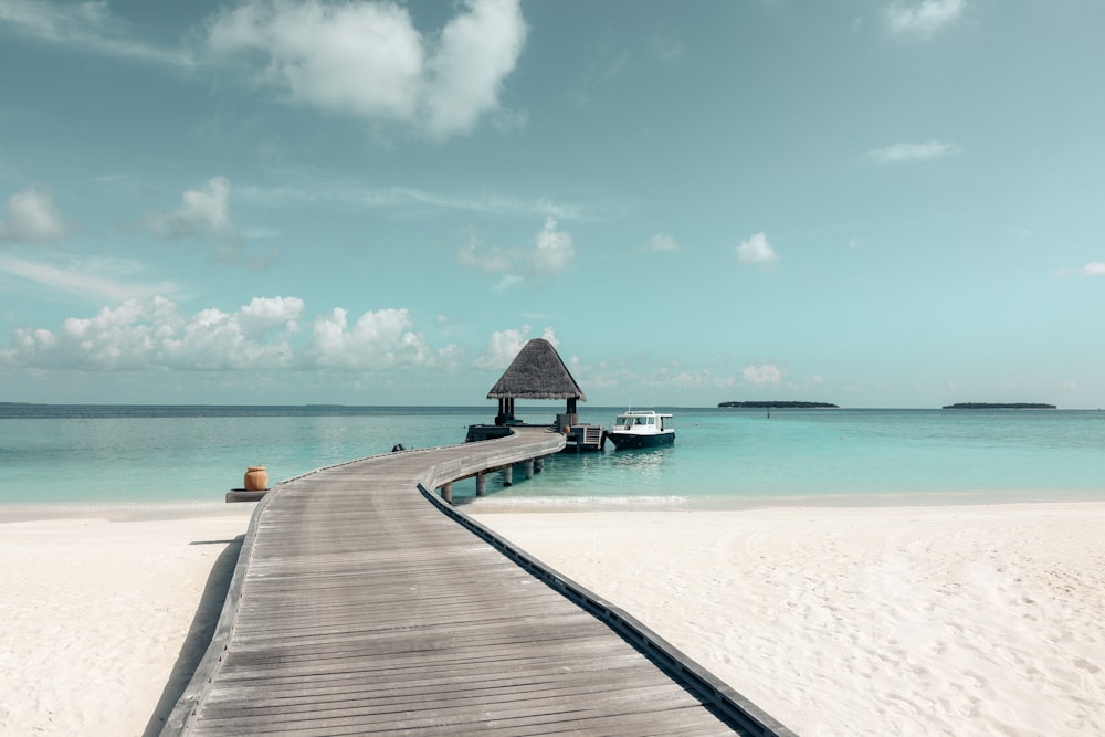 a dock leading to a beach with a boat in the water