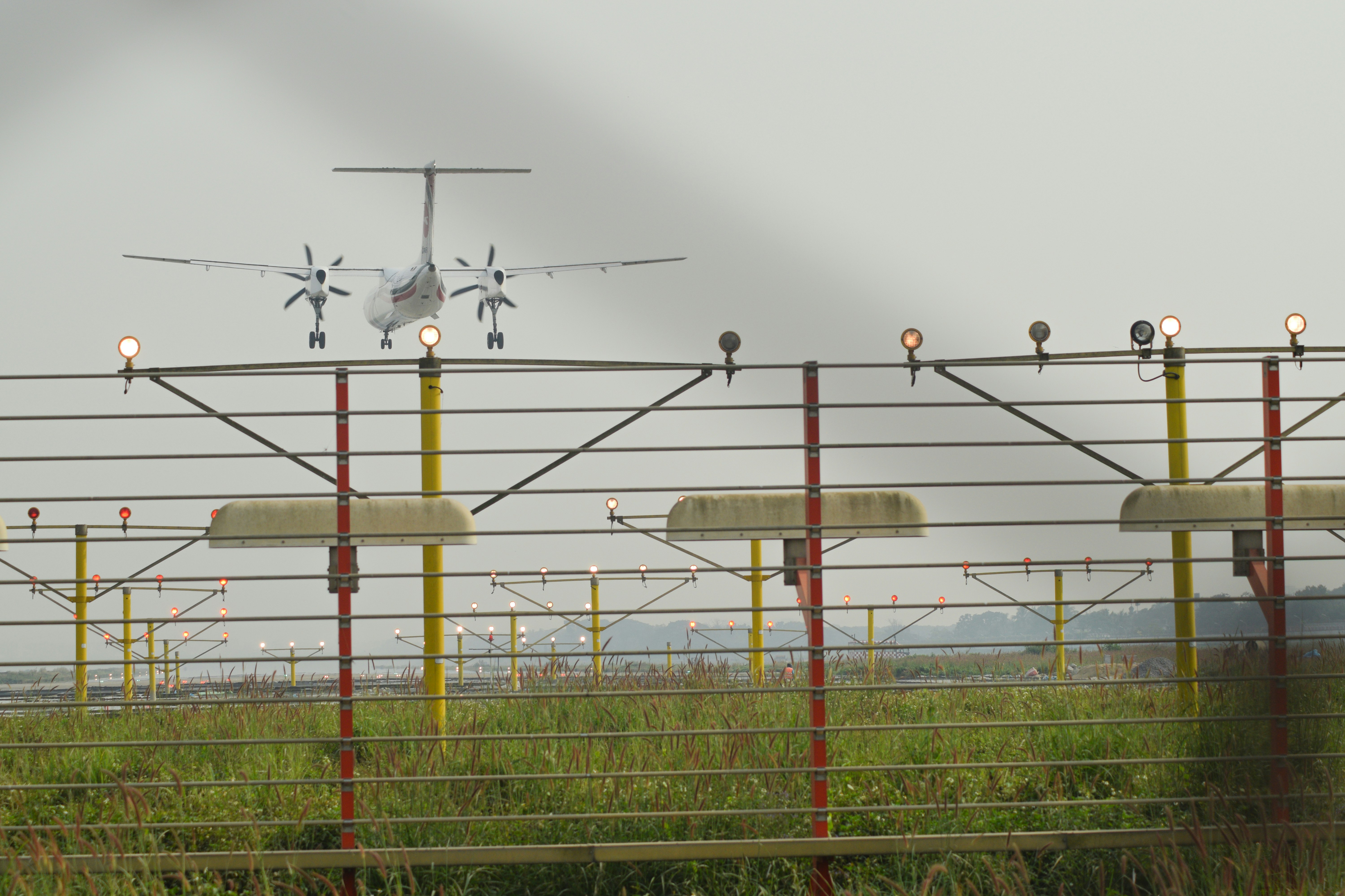 a small airplane is flying over a fence, Airplane landing on Hazrat Shahjalal International Airport Dhaka