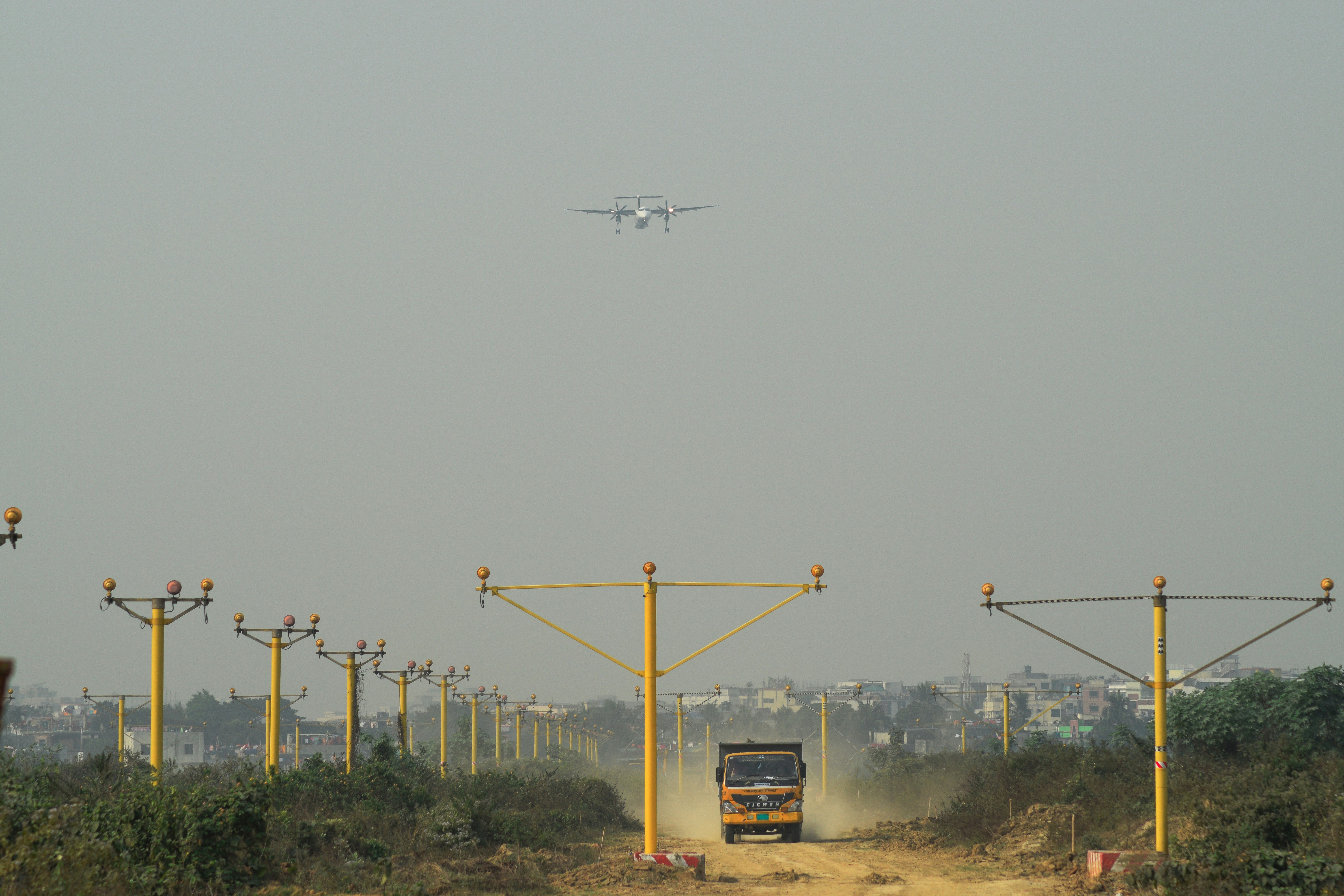 A small plane flying over a dirt road photo – Free Dhaka Image on Unsplash