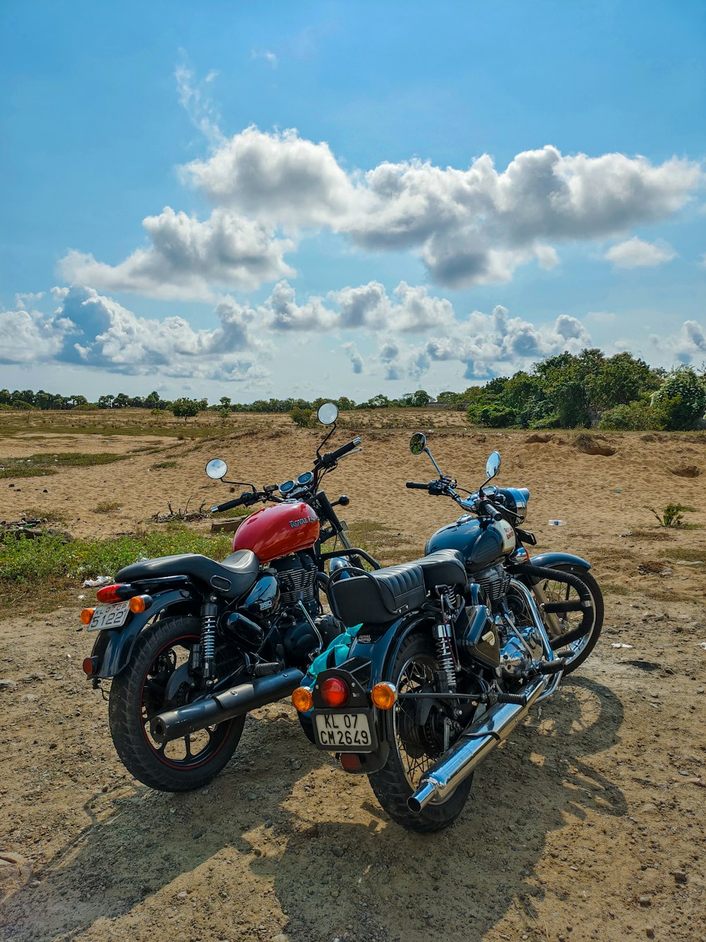 two motorcycles are parked on a dirt road